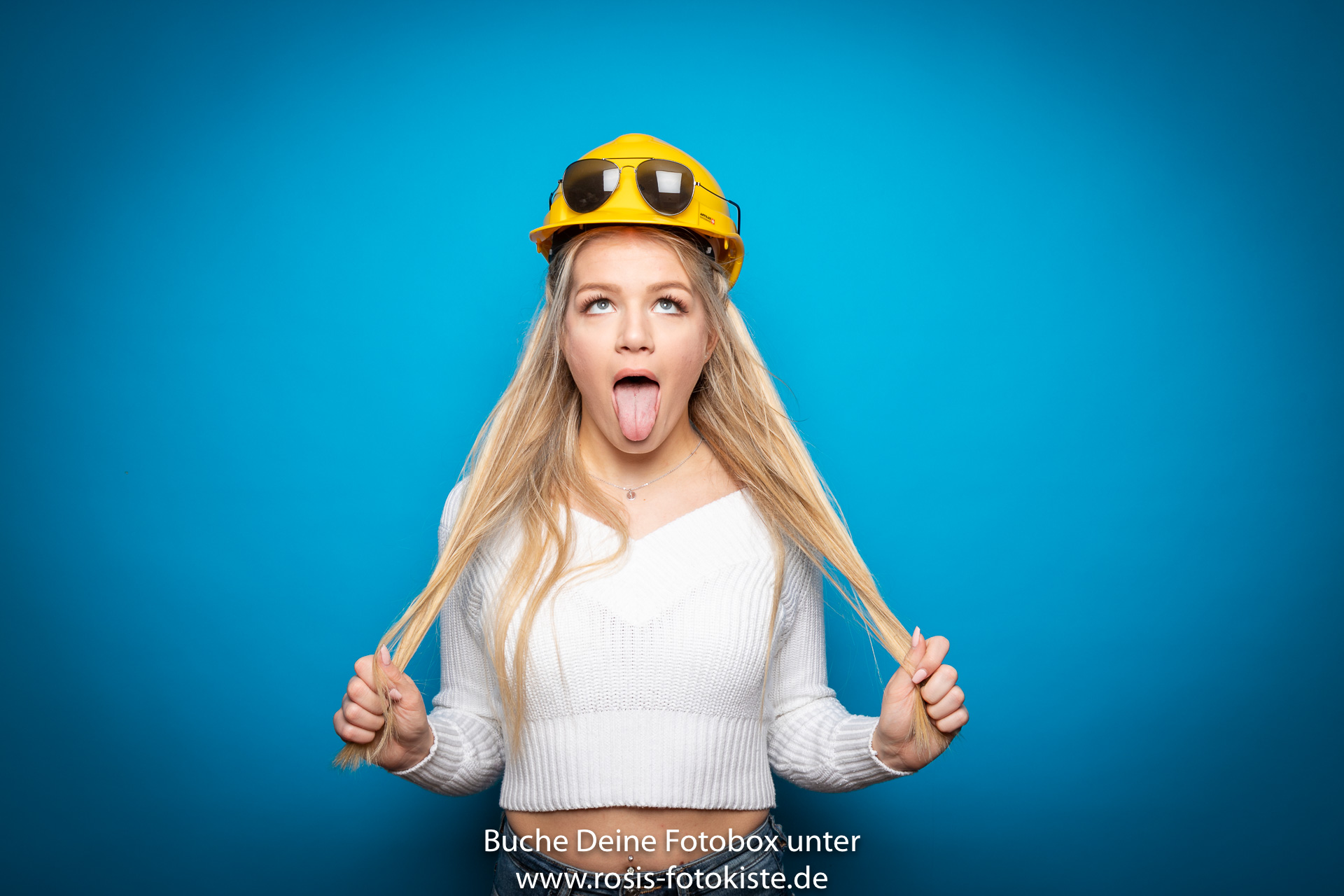 Blondes Mädchen lustig vor Rosis Fotokiste mit blauem Hintergrund
